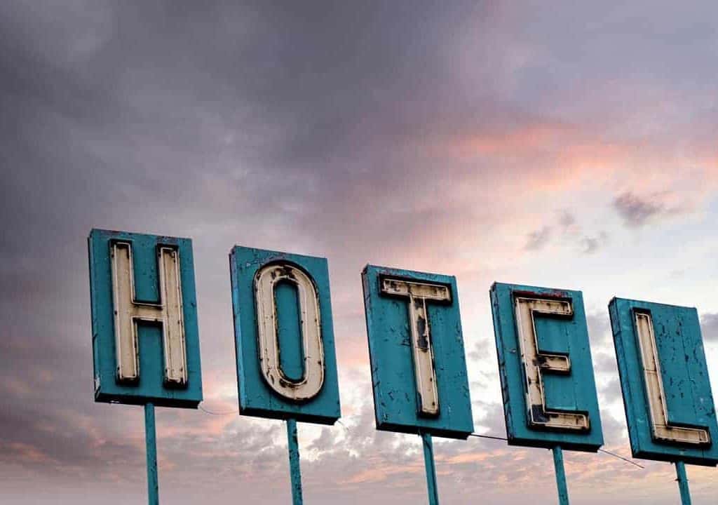 A battered and worn vintage neon hotel sign against a colorful sunrise sky near downtown Denver, Colorado.