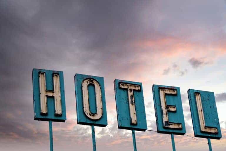 A battered and worn vintage neon hotel sign against a colorful sunrise sky near downtown Denver, Colorado.