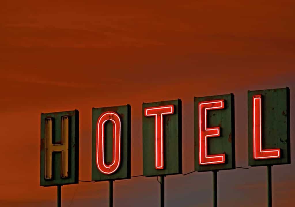 Vintage neon hotel sign under a bright orange sunset.