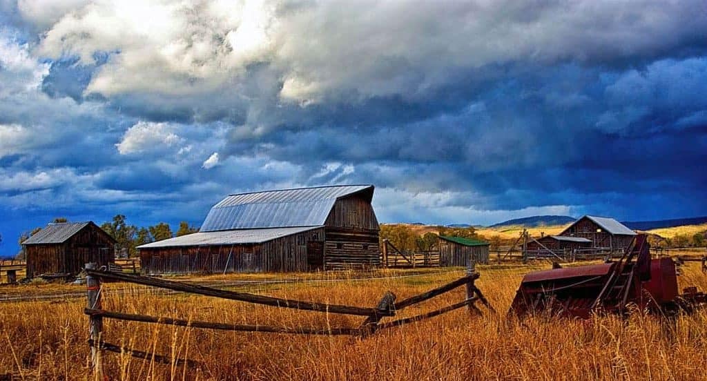 A dramatic sky highlights the old barns of Mormon Row in Grand Teton National Park, Wyoming.
