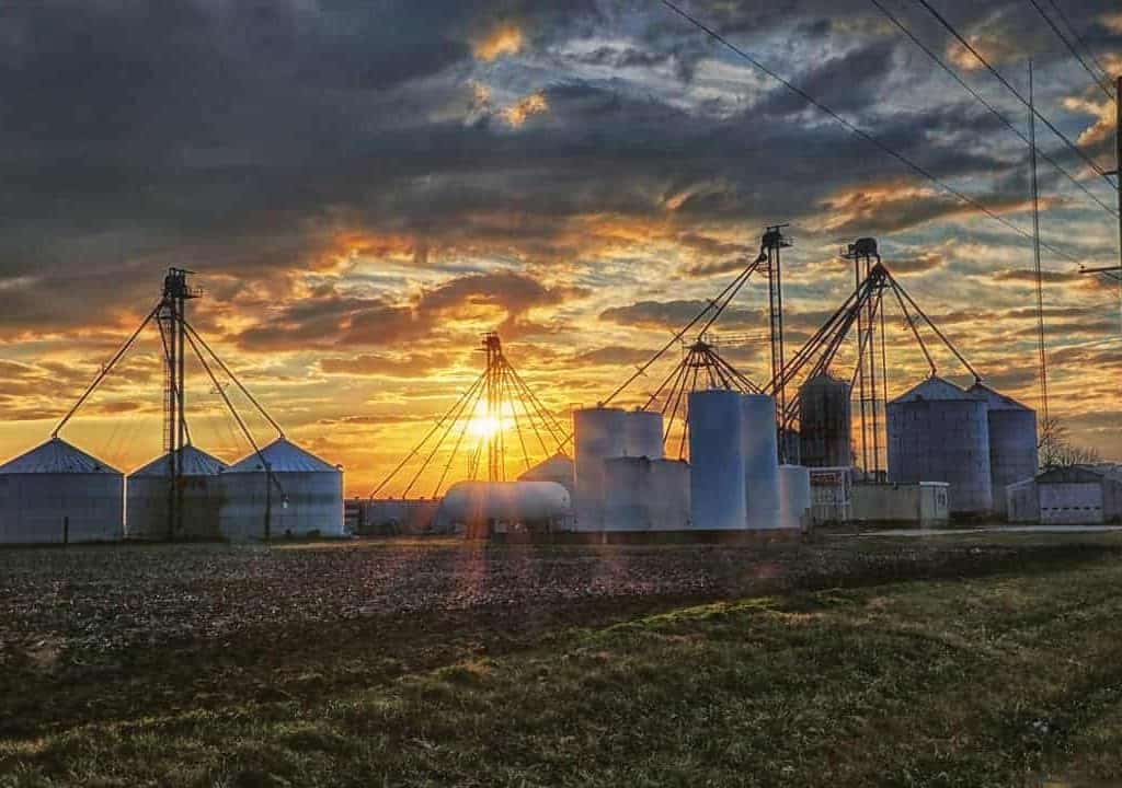 A dramatic rural central Illinois winter sunset over grain bins and silos.