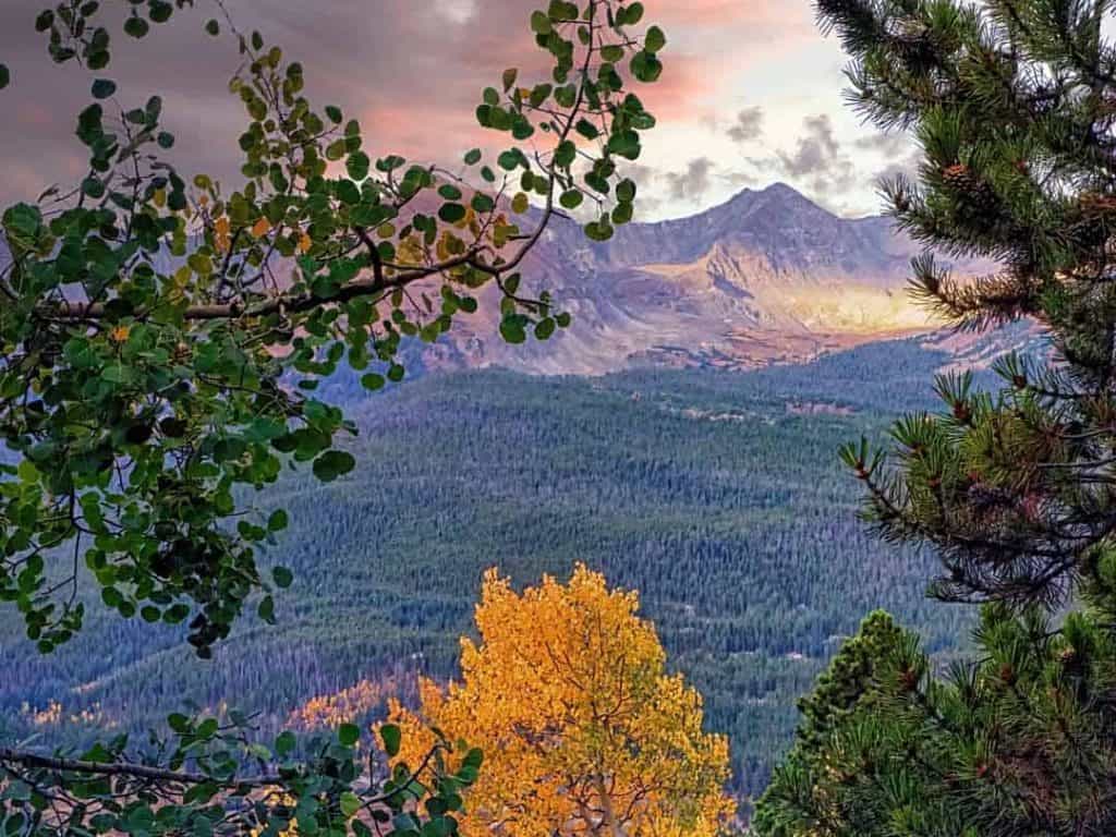 Early morning light on the peaks of the Ten Mile Range framed by colorful aspens and evergreens along Boreas Pass Road near Breckenridge, Colorado.