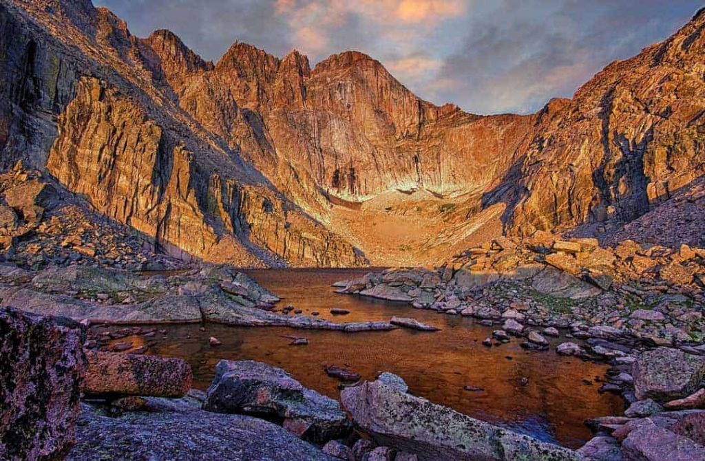 Located on the east side of Rocky Mountain National Park, Chasm Lake fills a deep cirque carved from the base of Mt. Meeker (13,911'), Longs Peak (14,259' and the highest point in the park), and Mt. Lady Washington (13,281'). The famous east-facing wall of Longs Peak known as "the diamond" rises 2,456' above this calm alpine lake which sits at 11,760'. Starting two hours before daybreak I made my way up the 4.2 miles to the lake mostly in the dark and arrived a little before sunrise and just in time to capture this image of the early morning summer light casting an orange glow on the peaks and surface of the water.