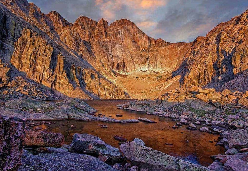Located on the east side of Rocky Mountain National Park, Chasm Lake fills a deep cirque carved from the base of Mt. Meeker (13,911'), Longs Peak (14,259' and the highest point in the park), and Mt. Lady Washington (13,281'). The famous east-facing wall of Longs Peak known as "the diamond" rises 2,456' above this calm alpine lake which sits at 11,760'. Starting two hours before daybreak I made my way up the 4.2 miles to the lake mostly in the dark and arrived a little before sunrise and just in time to capture this image of the early morning summer light casting an orange glow on the peaks and surface of the water.