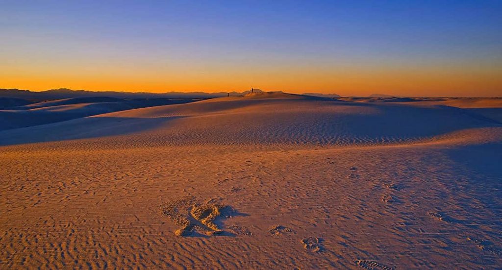 The fading daylight as the sun slips behind the San Andreas mountains casts the dunes of White Sands National Monument in orange.