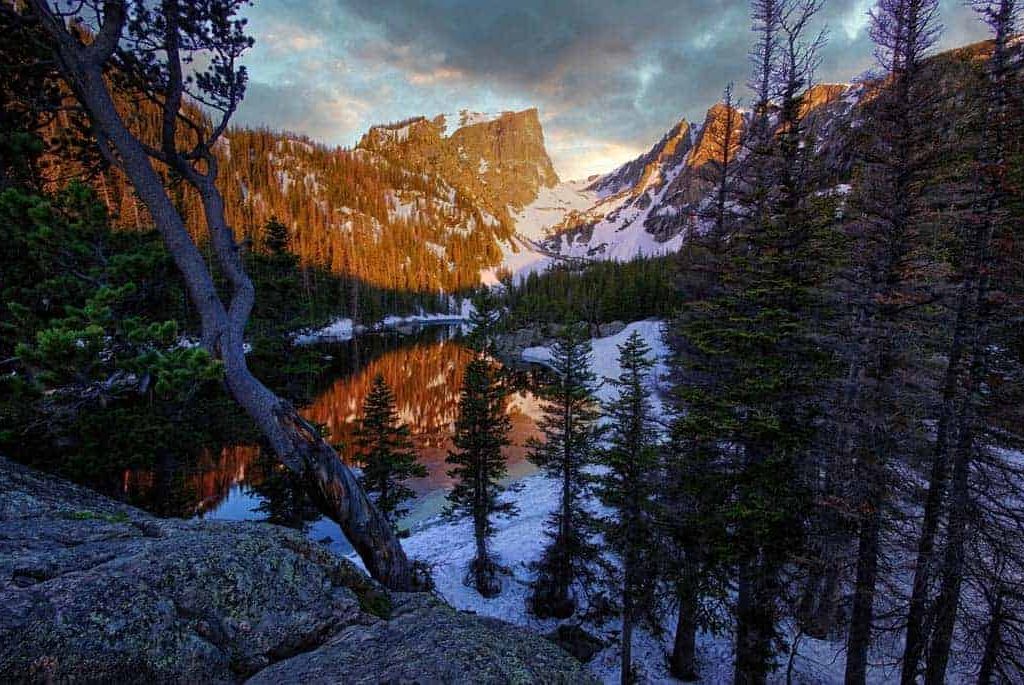 Hallett Peak and the still water of Dream Lake in Rocky Mountain National Park are cast in red by the early morning light Even though its early June, late spring snow still rings the lake.