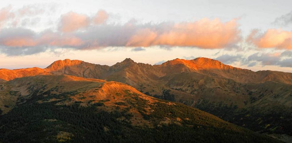 Early dawn light illuminates the peaks of the Rocky Mountains along the Continental Divide in Colorado. This multi-image sunrise panorama was shot on a crisp autumn morning from the summit of a neighboring 12,000' peak.
