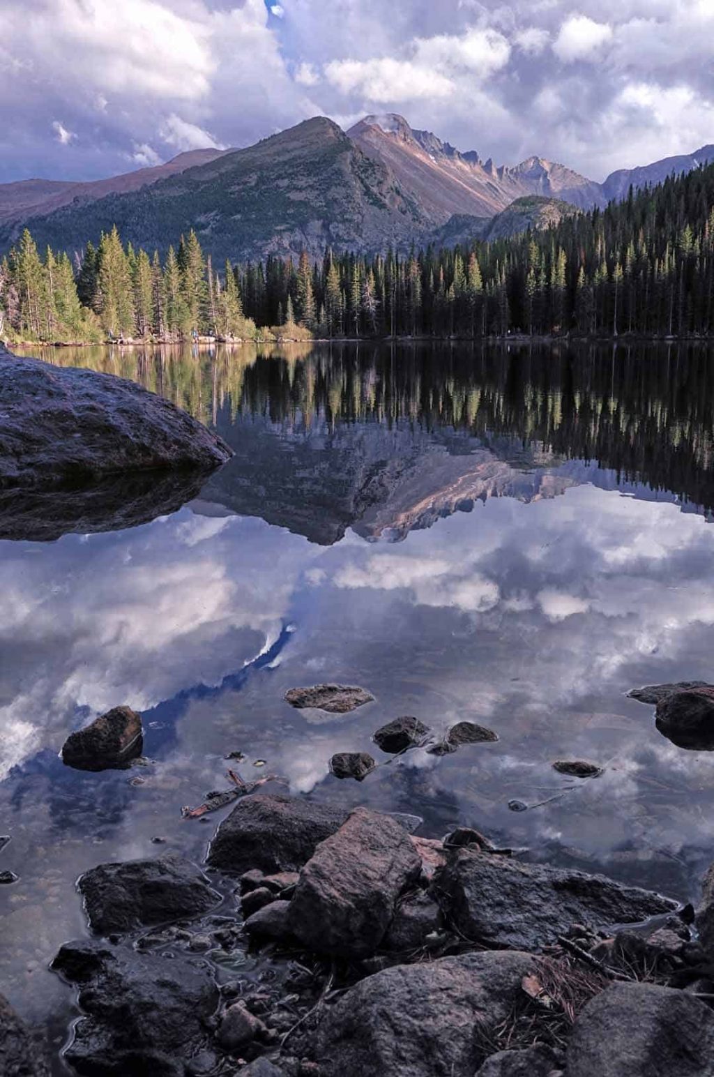 The only mountain risking above 14,000 in Rocky Mountain National Park, Longs Peak is reflected in the glass-like water of Bear Lake on a cloudy autumn evening.