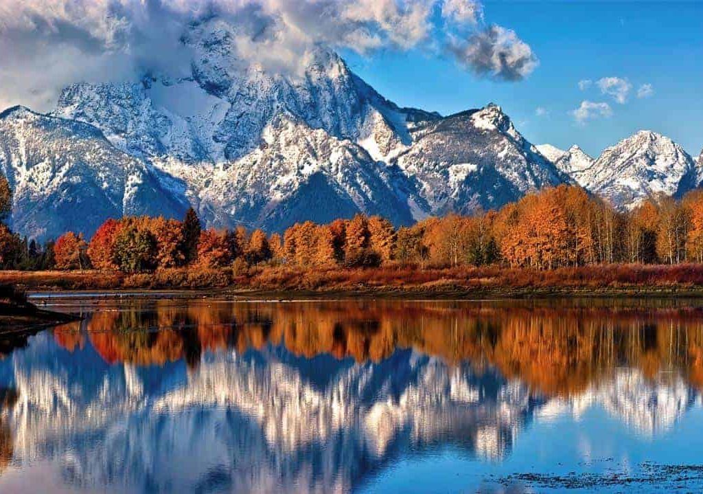 With its summit shrouded in clouds, Mount Moran is reflected in the still water of the Snake River at Oxbow Bend on a cool fall morning in Grand Teton National Park, Wyoming.