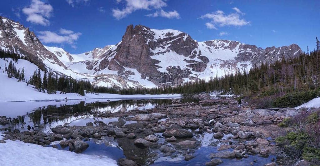 Distinctive Notchtop Mountain towers over the snow covered shores of Lake Helene in Rocky Mountain National Park, Colorado. Despite being early June, the area remains under a thick blanket of snow thanks to several late spring storms.