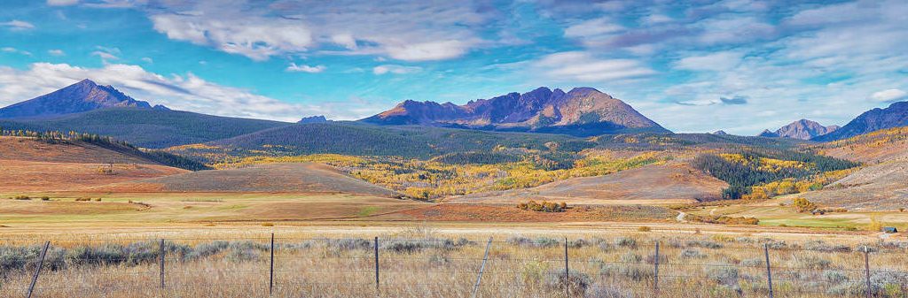 Colorful autumn hues blanket the rolling ranch land and forested hills at the foot of the Gore Range. This is three image panorama taken along Highway 9 north of Silverthorne, Colorado.