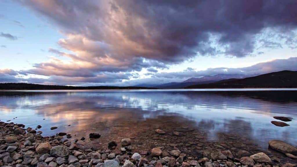 Sweeping cloud formations light by first rays of sunrise and reflected in the still waters of Turquoise Lake, near Leadville, Colorado.