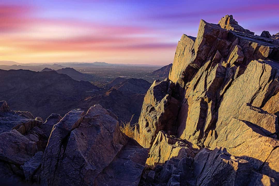 An amazingly colorful rainbow summer sunrise over the Phoenix Metro area framed by the rocky summit of Piestewa Peak. At 2,610 feet, Piestewa Peak is the 2nd highest peak in the Phoenix Mountains and named in honor of Army Spc. Lori Ann Piestewa, the first known Native American woman to die in combat in the U.S. military,and the first female soldier to be killed in action in the 2003 Iraq War.