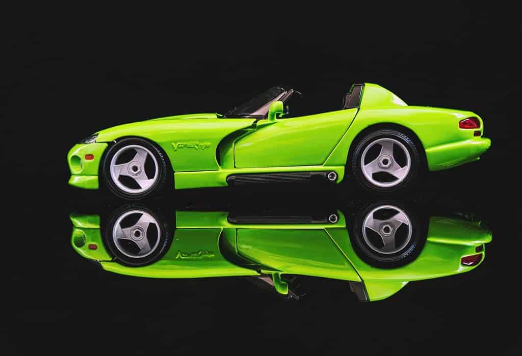 A lime green Dodge Viper RT/10 sports car reflected against a black background.