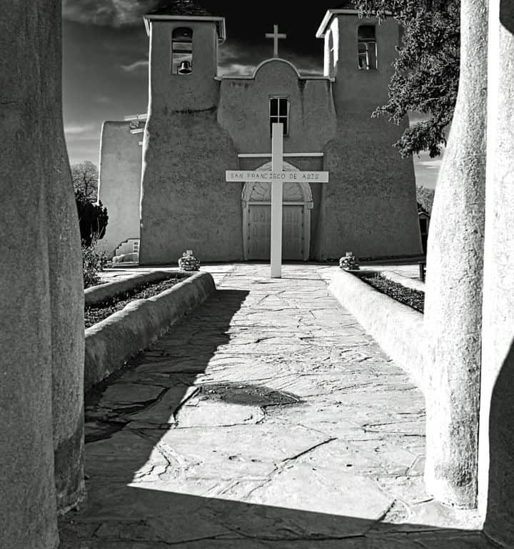 The historic San Francisco de Asis church in Rancho de Taos, New Mexico on a sunny late winter afternoon. With its twin bell towers and arched entry, this adobe church from the early 1800's blends Spanish colonial architecture and the building techniques of the Taos Pueblo people. Made famous by Ansel Adams and Georgia O'Keefe it is a National Historic Landmark and still an active church today.