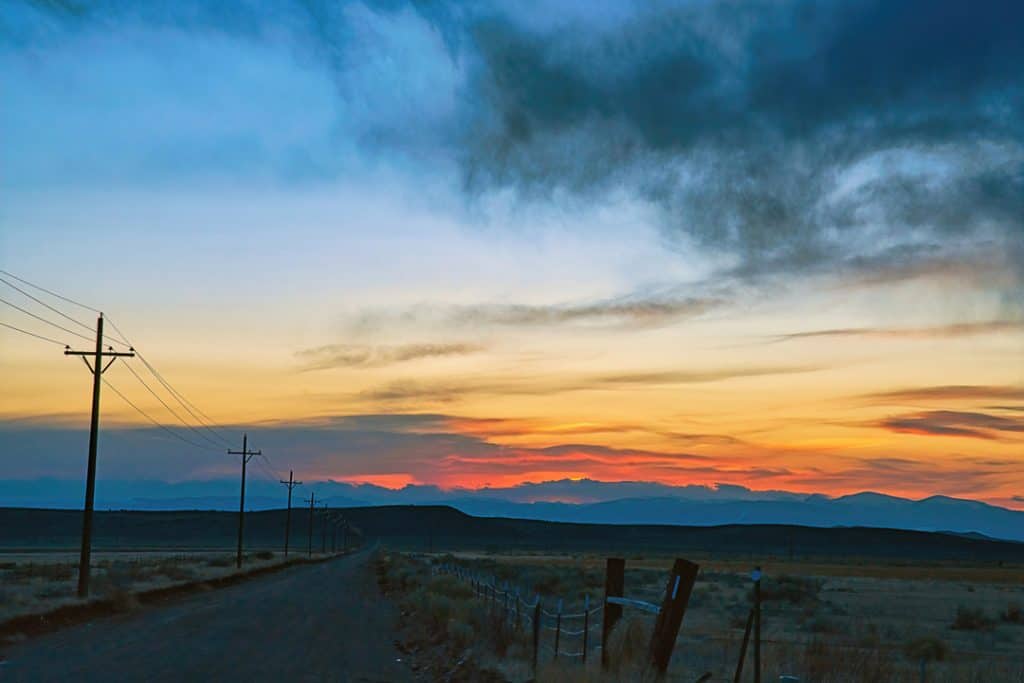 A dramatic late winter sunset over an empty road in rural Southern Colorado near the New Mexico border.