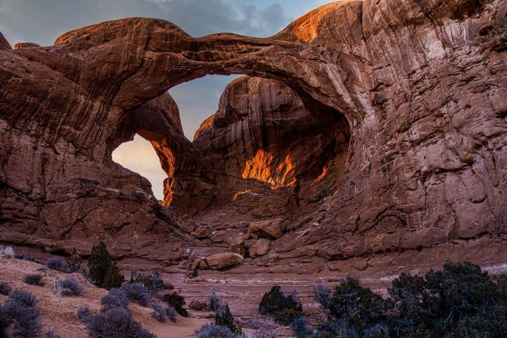 Glowing under the fading light of a winter sunset, Double Arch makes an impressive scene. This distintive pair of close-set arches is located in The Windows section of Arches National Park in Utah. At 112' high and 144' wide the larger of the two arches is the tallest and second longest arch in the park. The smaller arch is 67' wide.