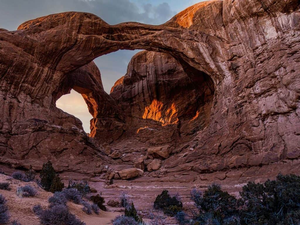 Glowing under the fading light of a winter sunset, Double Arch makes an impressive scene. This distintive pair of close-set arches is located in The Windows section of Arches National Park in Utah. At 112' high and 144' wide the larger of the two arches is the tallest and second longest arch in the park. The smaller arch is 67' wide.