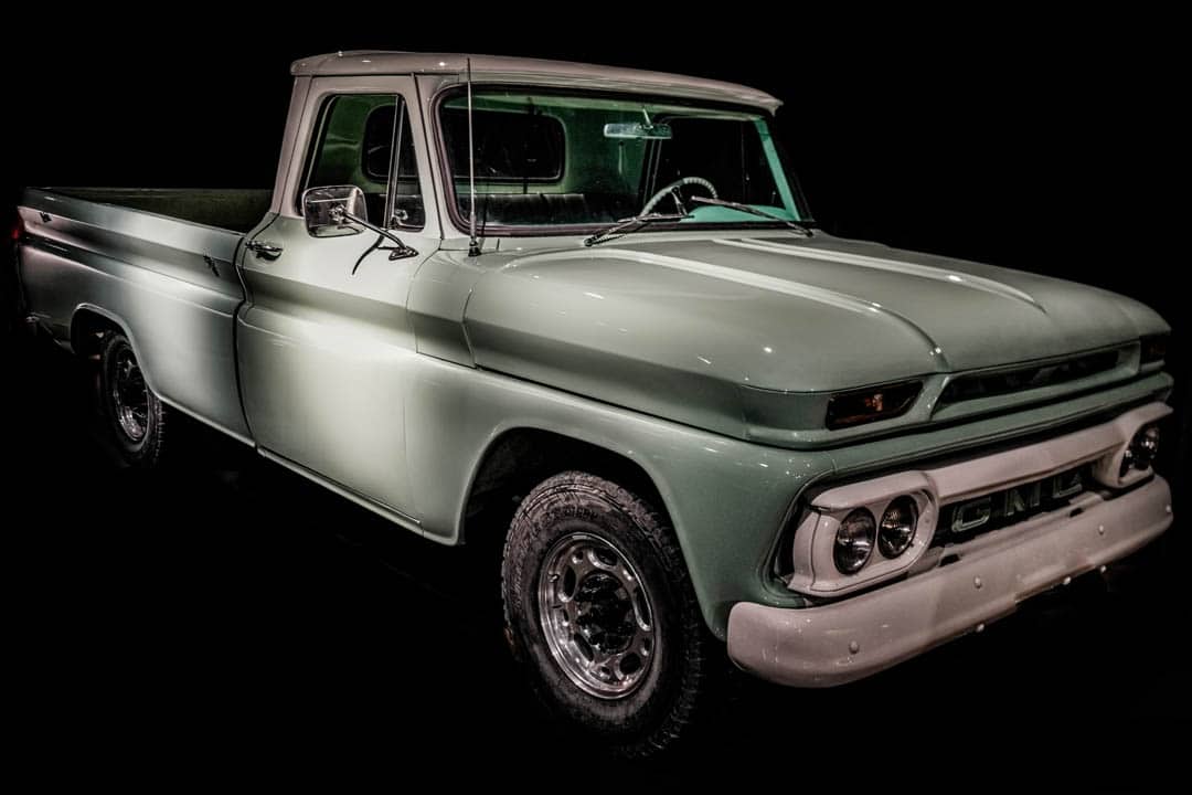 A nicely restored vintage GMC 1966 C10 pick up truck in light green paint.