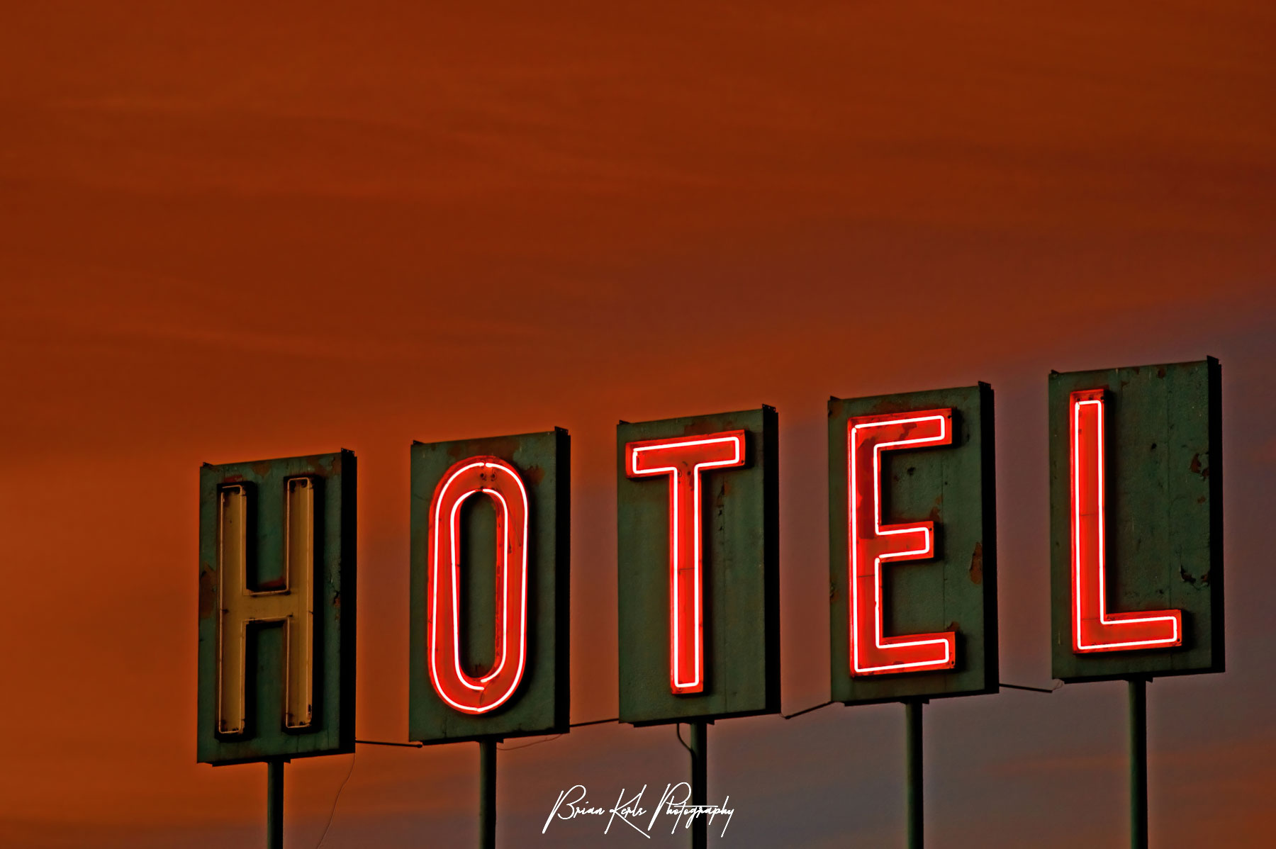 Orange glow of sunset highlights a worn and battered hotel sign near Denver, Colorado.