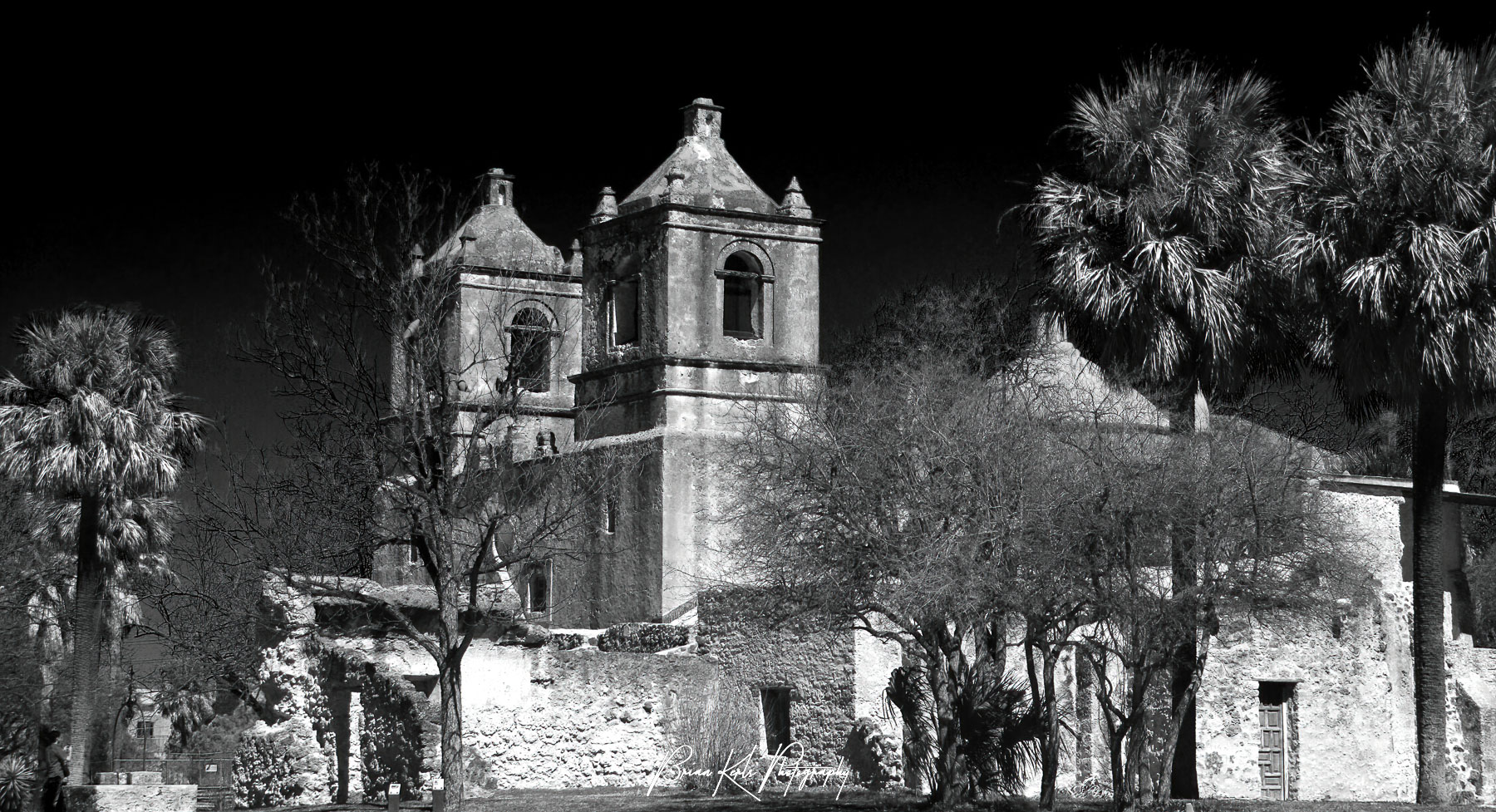 The striking contrast between the deep blue afternoon sky and the light facade of Mission Concepcion in San Antonio, Texas is captured in this black and white image.