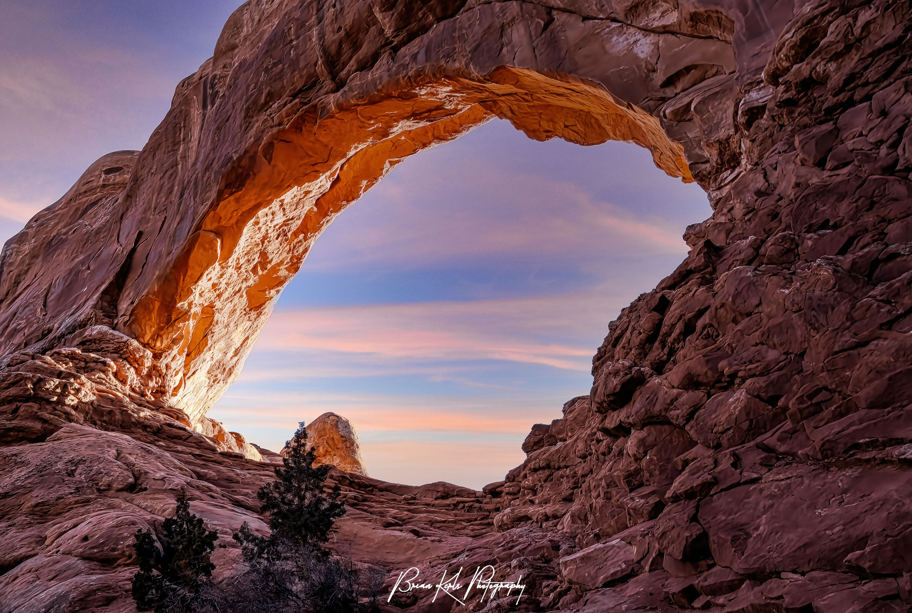 With its large collection of unique and interesting arches, The Windows section of Arches National Park in Utah is a must see destination. This view looking up through the North Window arch as the rim glows in the golden rays of sunset wash taken from the east side on the primitive trail that circles the North and South Windows.