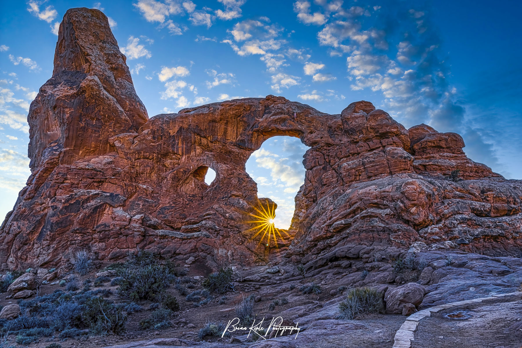 A starburst shines through distinctive Turret Arch in Arches National Park, Utah during a winter sunset. Turret Arch is one of the more impressive natural arches in the popular Windows area of the park.