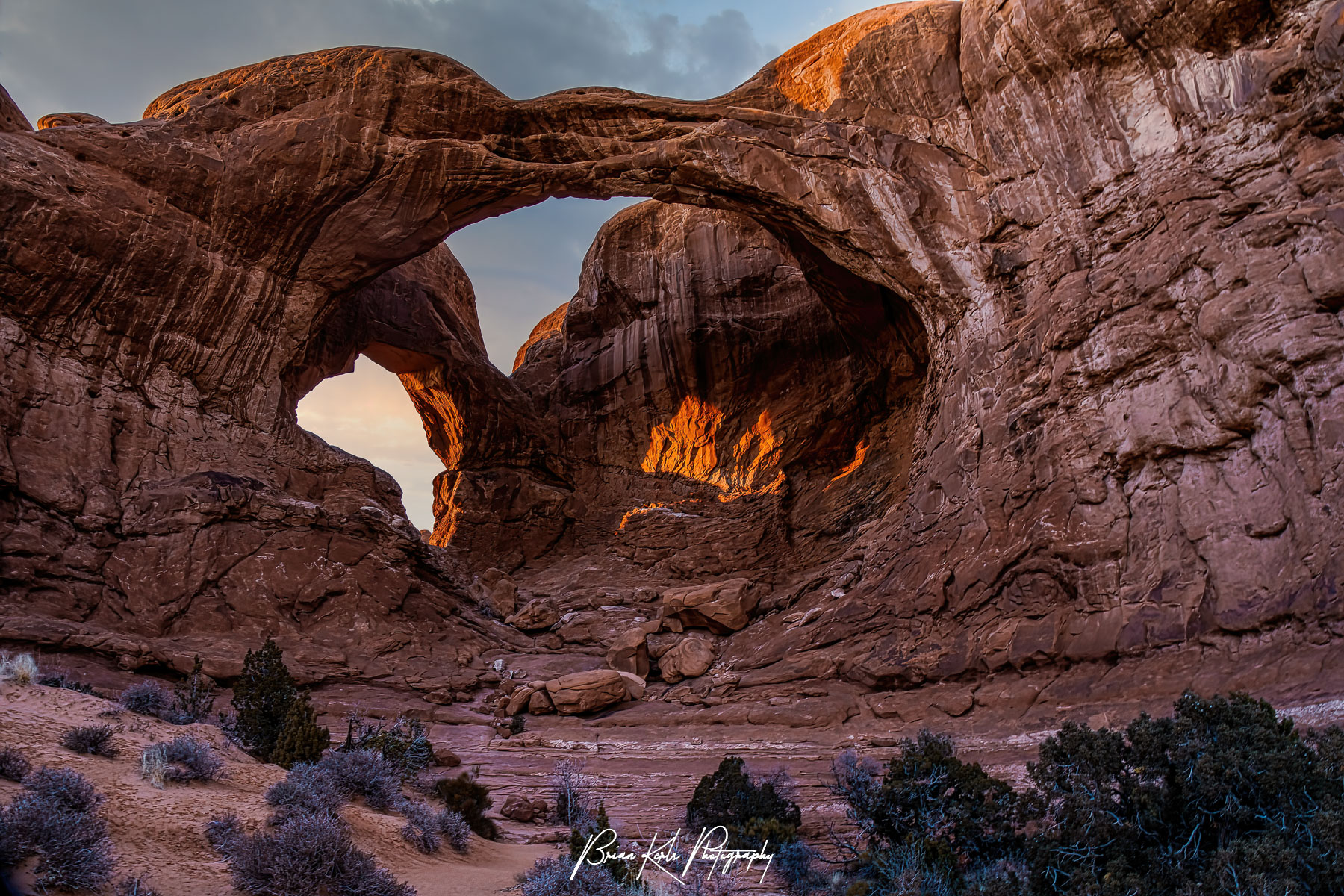 Glowing under the fading light of a winter sunset, Double Arch makes an impressive scene. This distintive pair of close-set arches is located in The Windows section of Arches National Park in Utah. At 112' high and 144' wide the larger of the two arches is the tallest and second longest arch in the park. The smaller arch is 67' wide.