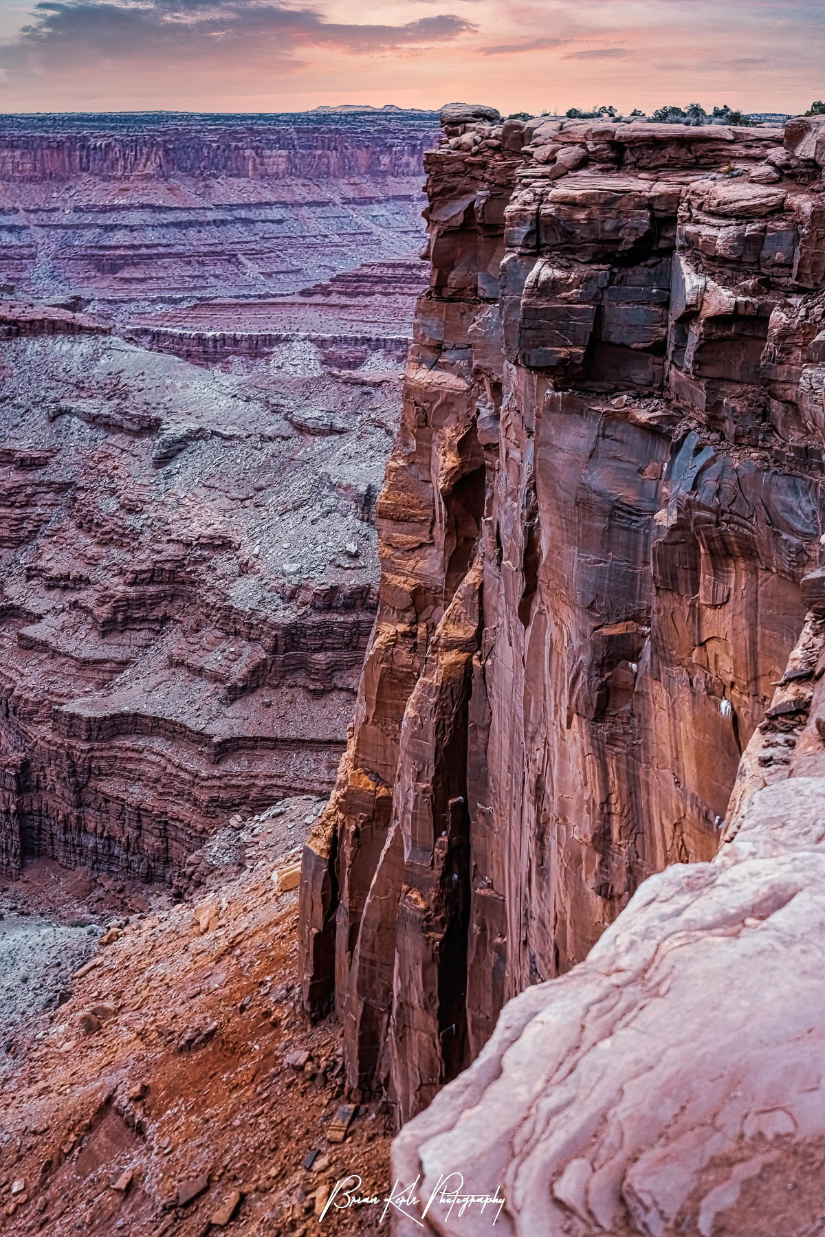 The sheer sandstone cliffs of the Dead Horse Point overlook in Utah are tinged with the fading colors of a simple winter sunset. Carved by centures of ice, water, and wind the vertical walls of these sandstone canyons create one of the more dramatic and rugged landscapes of the American Southwest. The name, Dead Horse Point State Park, has curious origins. It is said to come from cowboys in the 1800's who used the high plateau as a natural corral, but not without consequences as horses often died of exposure.