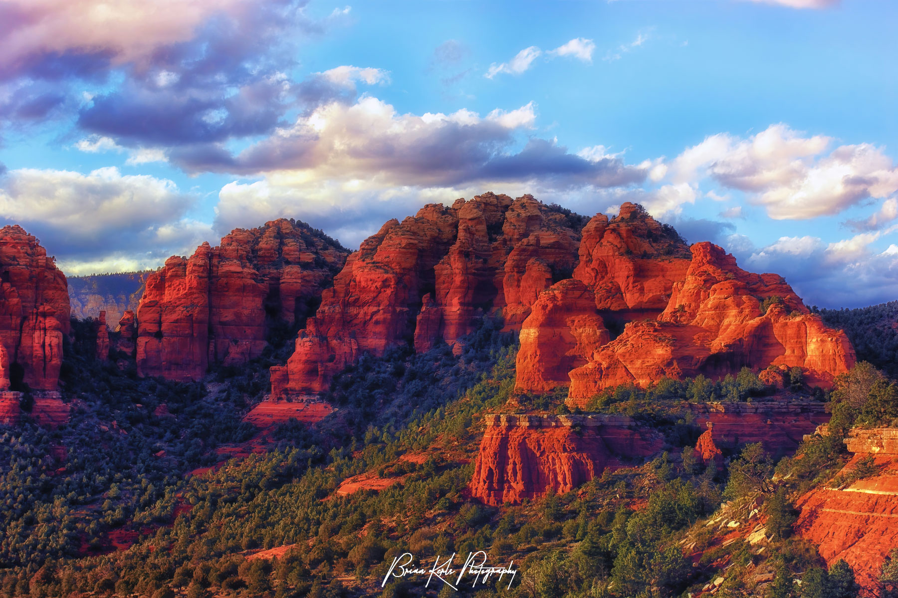 The setting sun illuminates the beautiful red rock cliffs, pillars, and formations outside of Sedona, Arizona on an autumn evening.