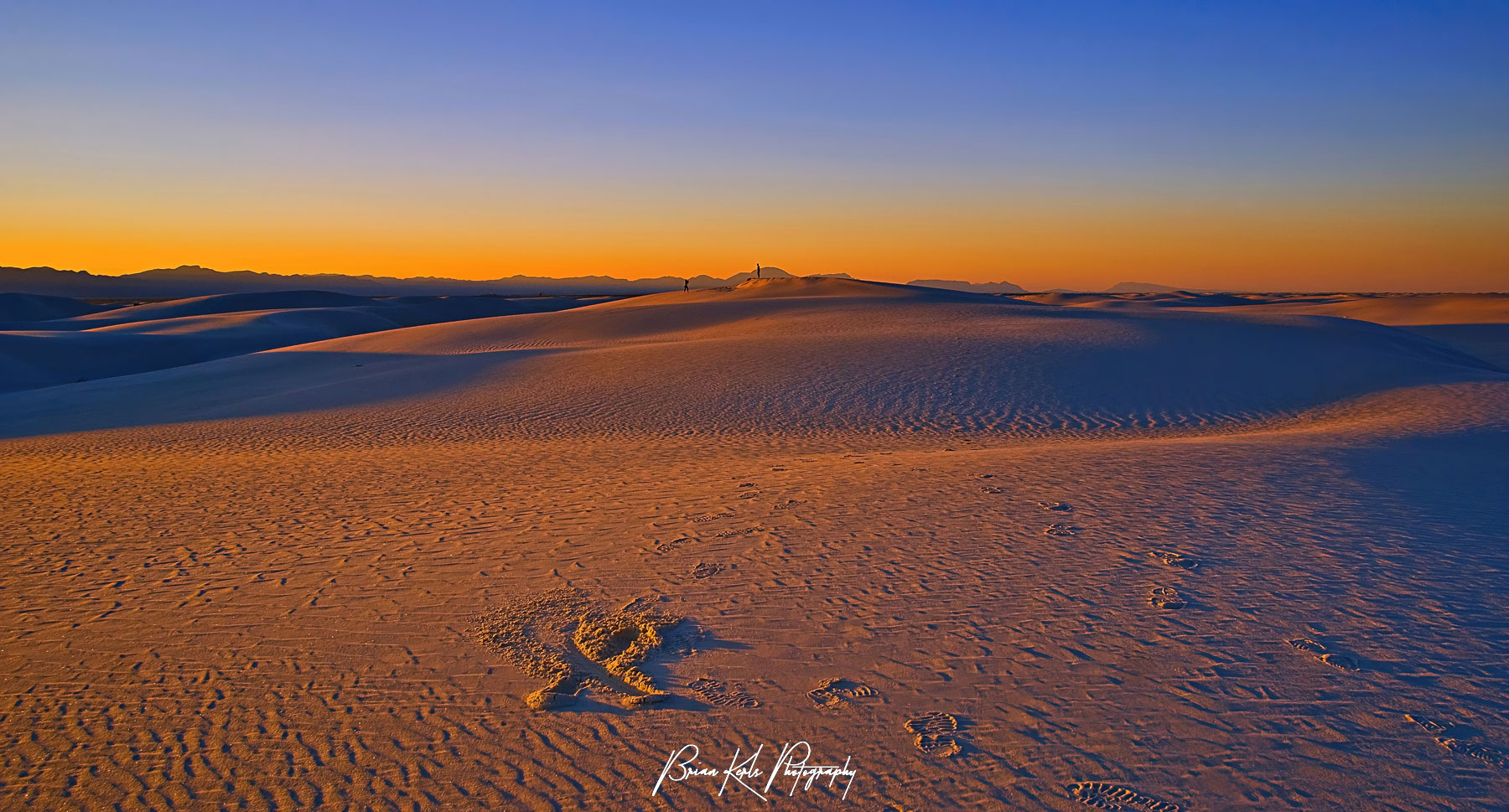 The fading daylight as the sun slips behind the San Andreas mountains casts the dunes of White Sands National Monument in orange.