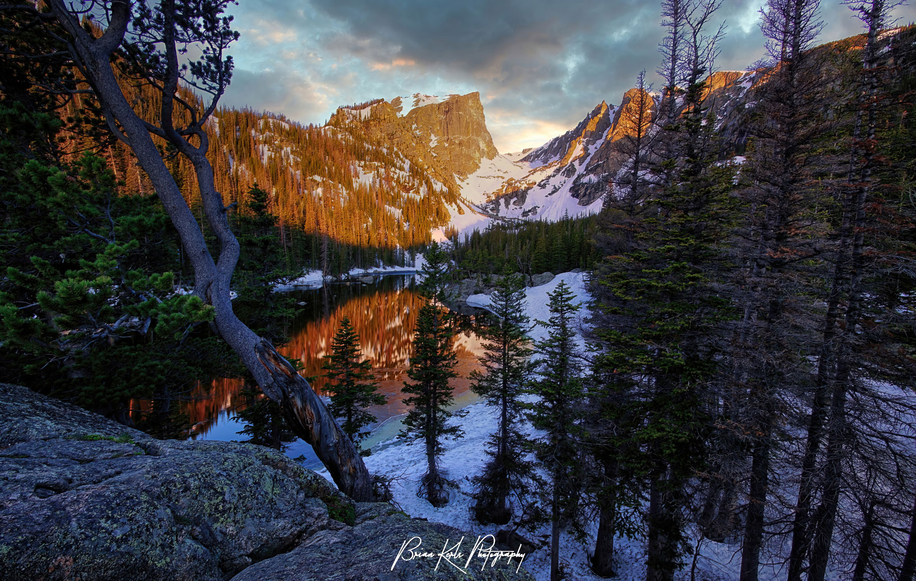 Hallett Peak and the still water of Dream Lake in Rocky Mountain National Park are cast in red by the early morning light Even though its early June, late spring snow still rings the lake.