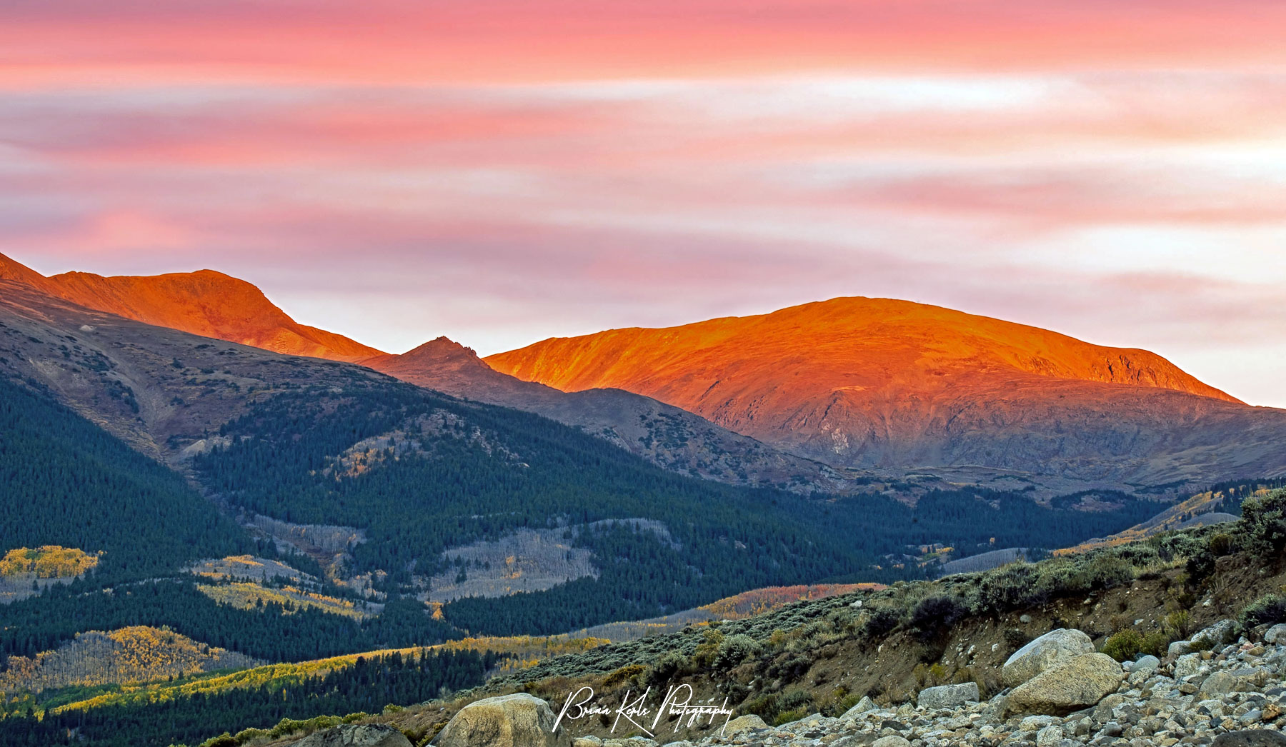 The peaks of the Sawatch Range in Colorado glow red in the dawn light early on an autumn morning.