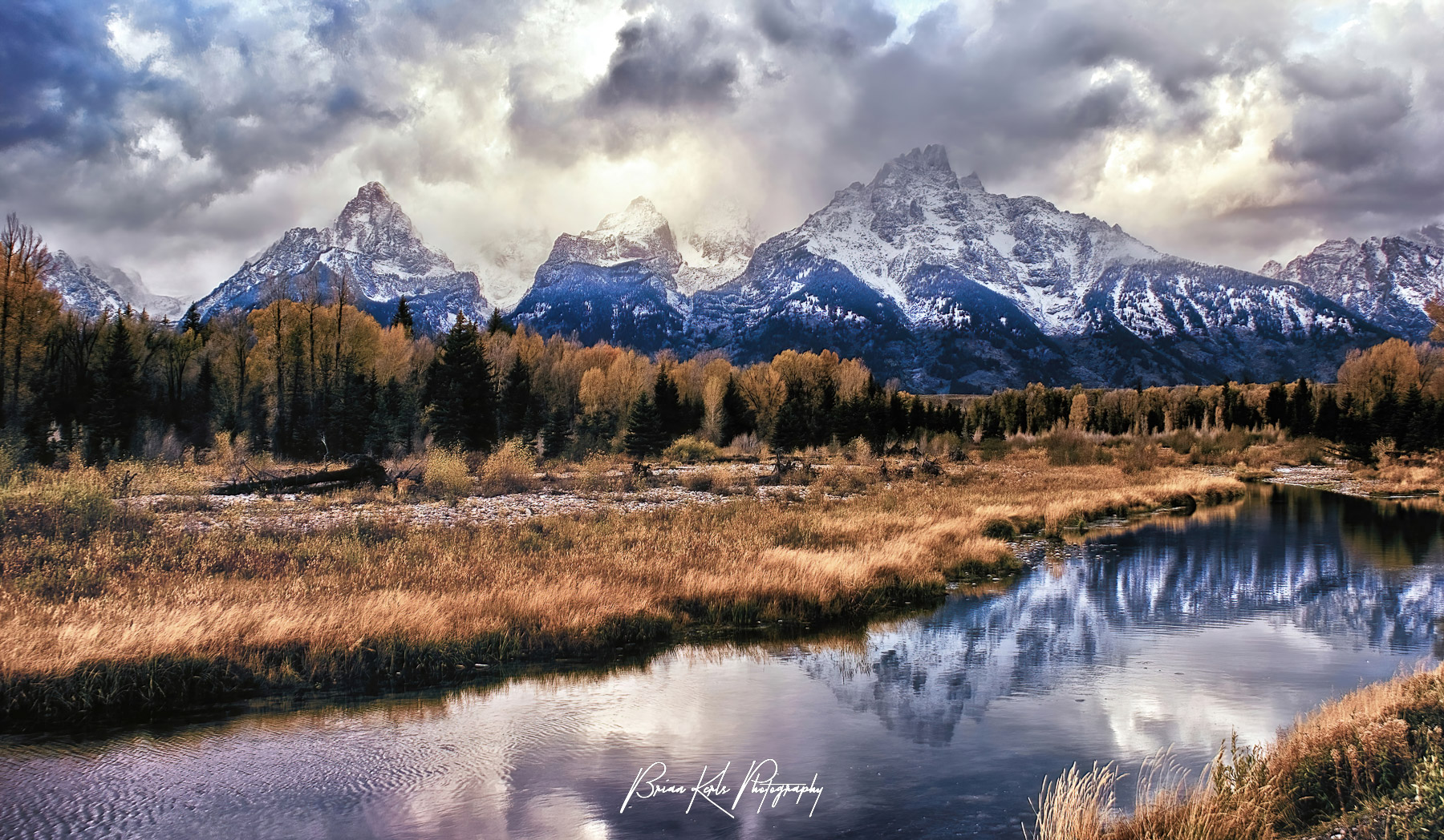 The setting sun illuminates the jagged peaks of the Tetons as an autumn storm rolls in.