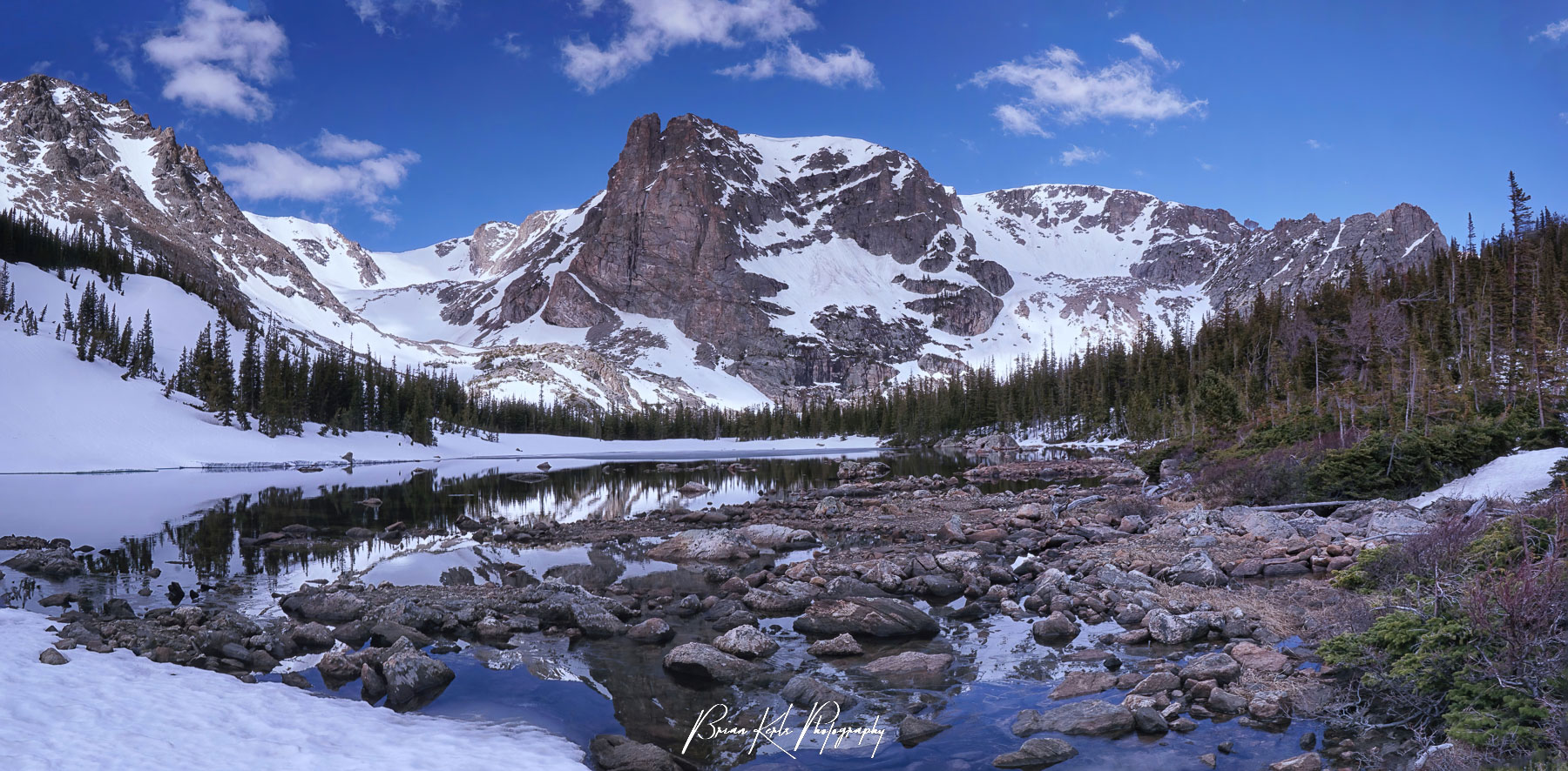 Distinctive Notchtop Mountain towers over the snow covered shores of Lake Helene in Rocky Mountain National Park, Colorado. Despite being early June, the area remains under a thick blanket of snow thanks to several late spring storms.