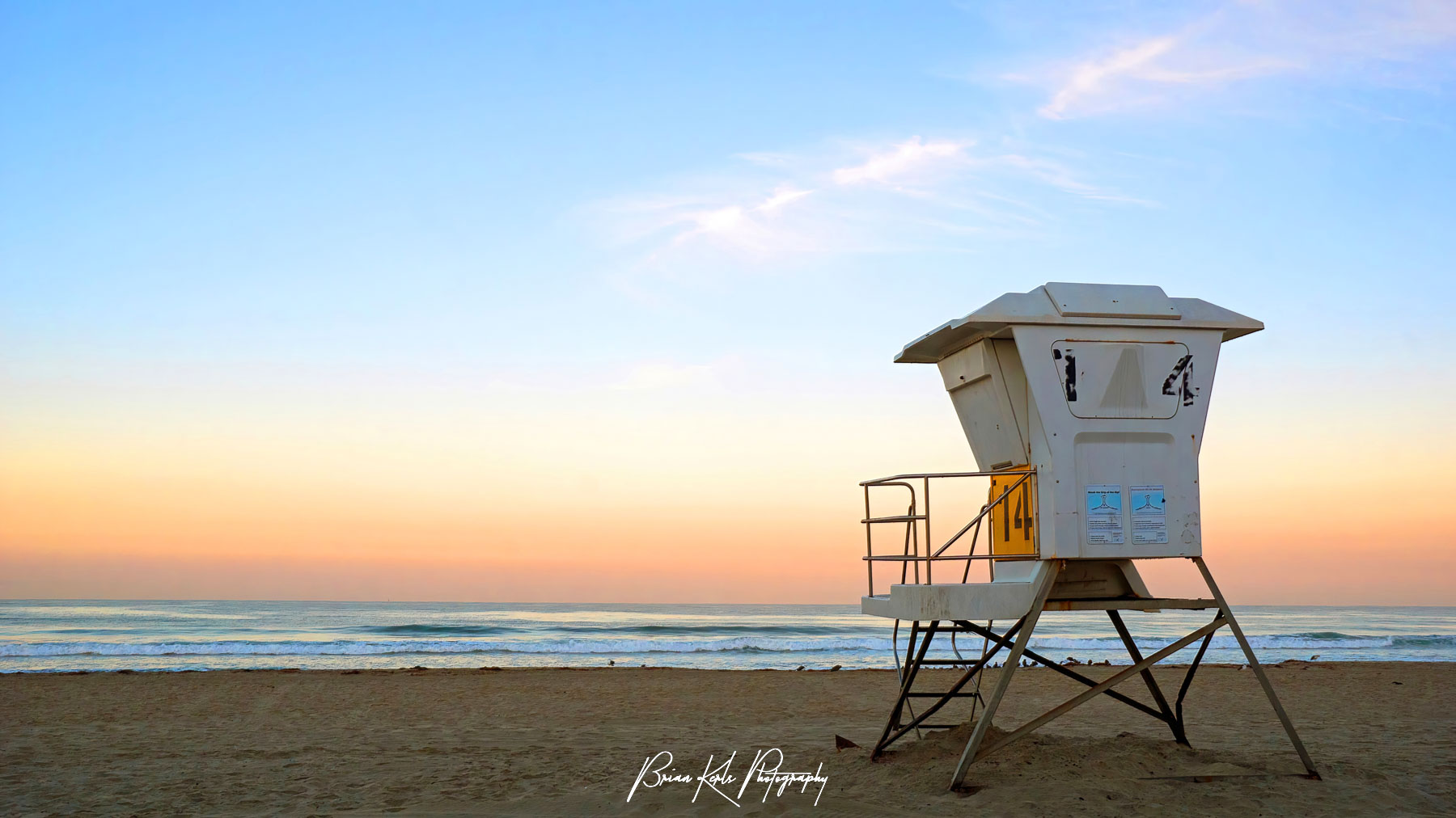 Beautiful orange light on the horizon and a gentle Pacific surf greets a new day on the California coast on Mission Beach in San Diego, California.