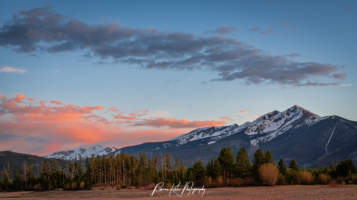 As the clouds are brushed in the soft pink hues of sunset, Peak One - timeless, patient, and unmoved - watches over Frisco, CO and the forests below.
