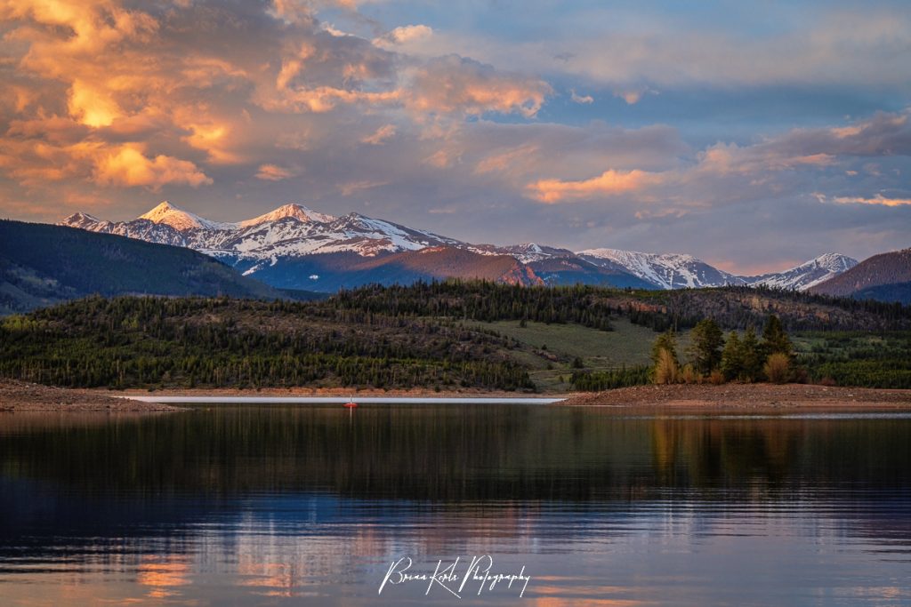 Grays and Torreys Peaks bathed in alpenglow light by a colorful spring sunset painting the sky over Lake Dillon in Summit County, CO.