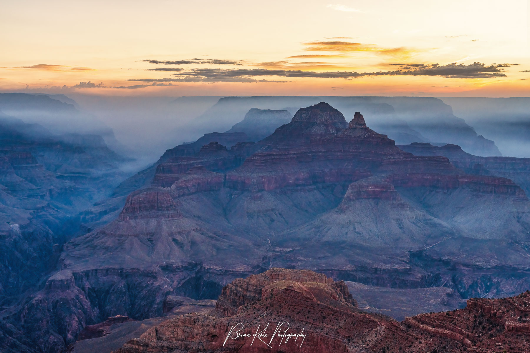 Fine art photograph of the Grand Canyon enveloped in smoke from Dragon Bravo wildfire during sunrise featuring layered rock formations, and a glowing pastel sky—ideal for nature wall art, Southwest landscape prints, and Grand Canyon decor.
